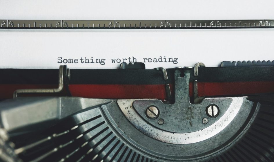 A page in a typewriter with the typed words 'Something worth reading'