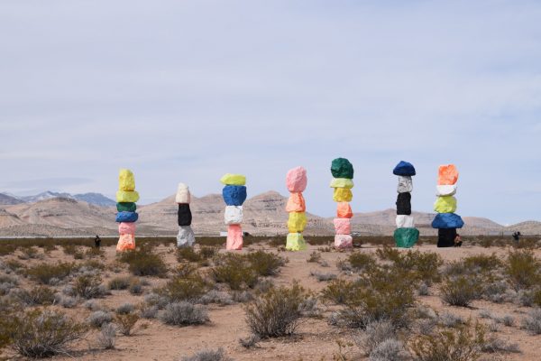 Seven stacks of colourful rocks in a desert landscape.