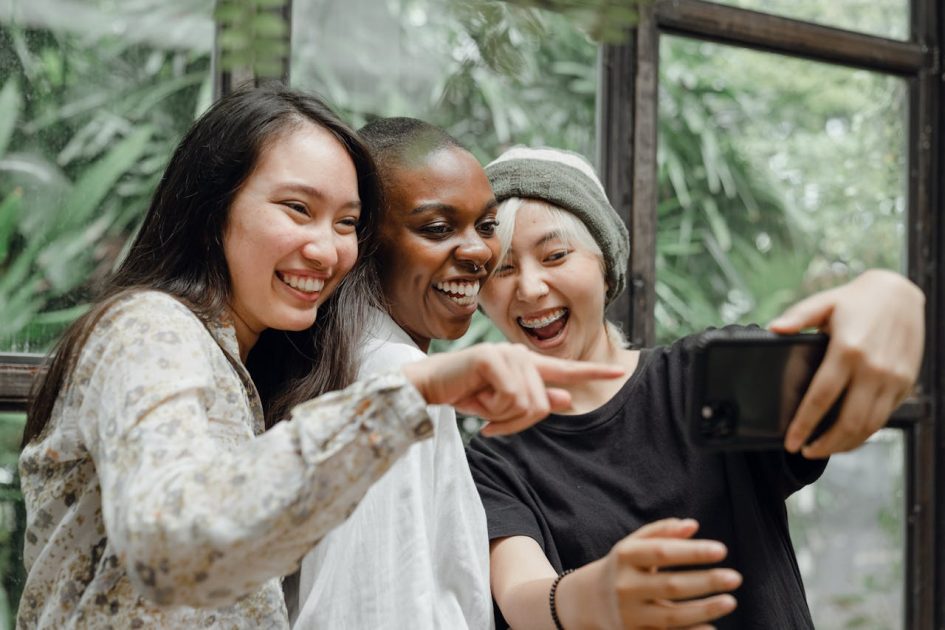 Cheerful female friends laughing at just taken selfie