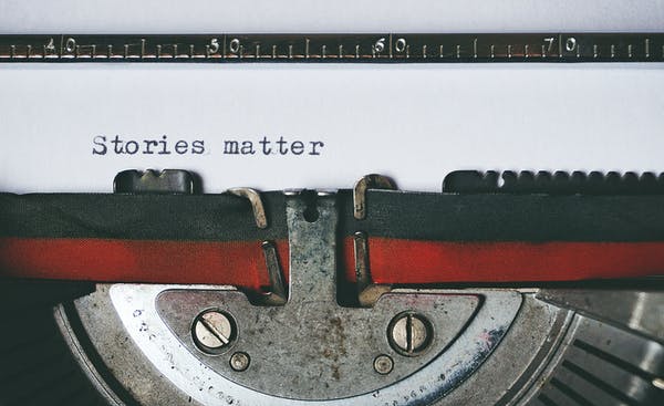 Typewriter with paper showing text that reads Stories matter.