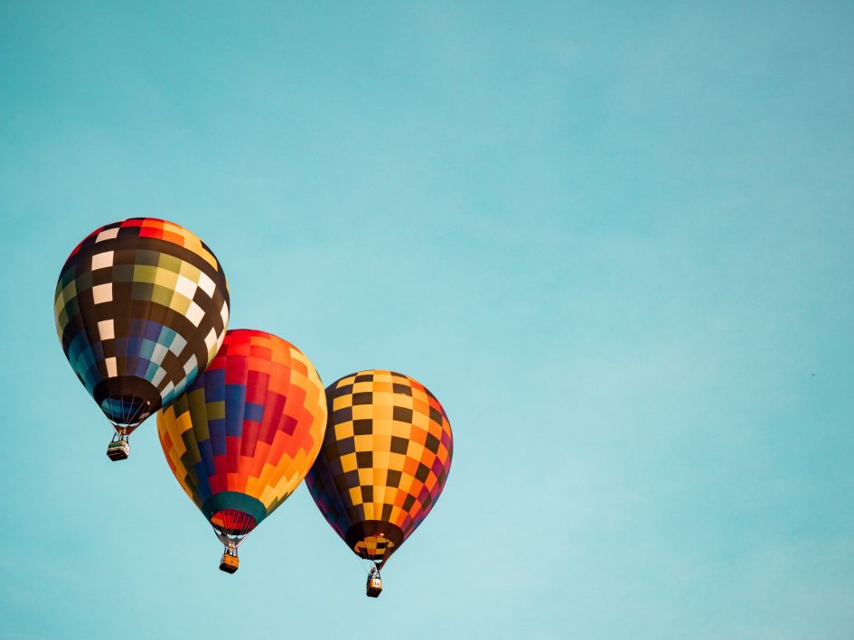 Three hot air balloons floating together in the sky.