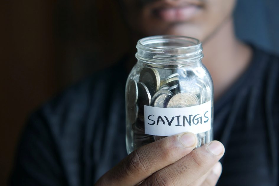Image of a person holding a jar of money labeled savings.