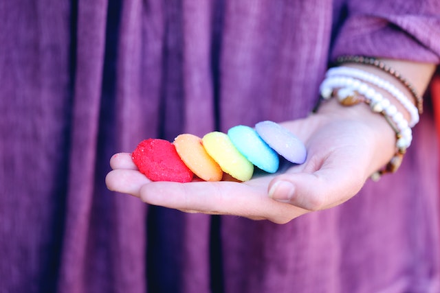 A hand offering up five brightly colored cookies