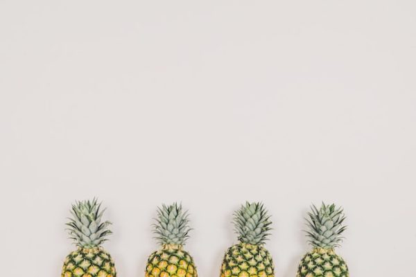 Four pineapples lined up against a wall