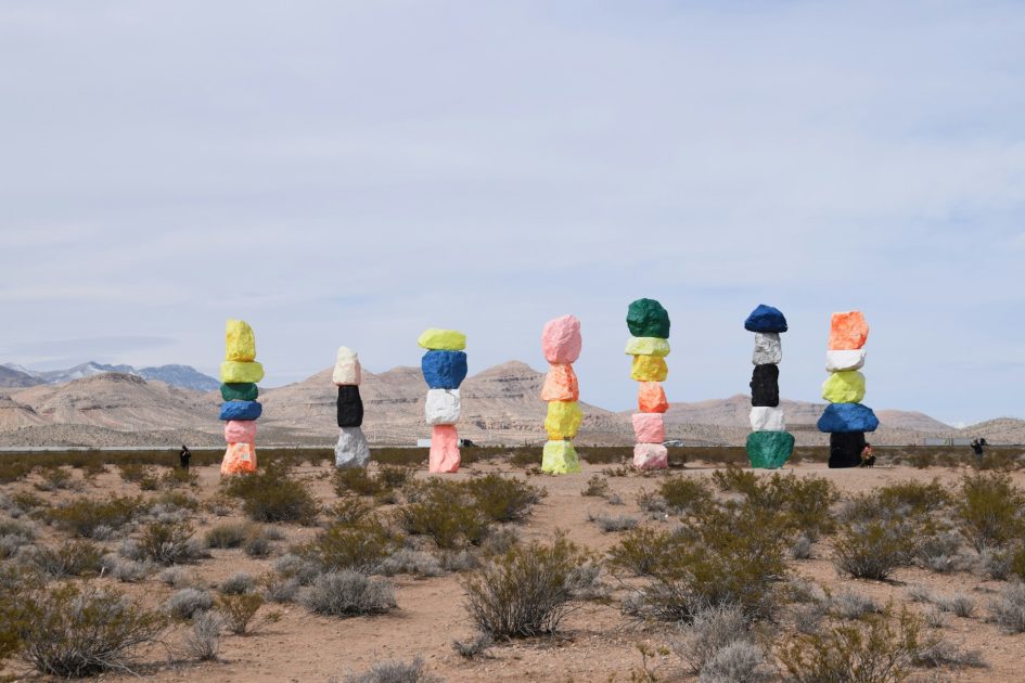 Seven piles of colorful rocks stacked in a desert landscape
