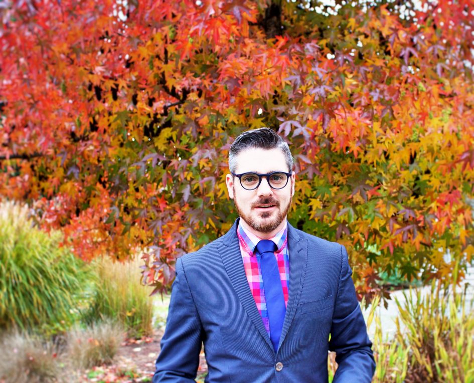 photo of Jesse Miller in a blue suit and wearing glasses