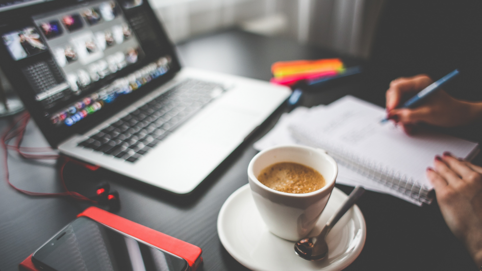 A laptop with a video conference open on it, a cup of coffee in the foreground